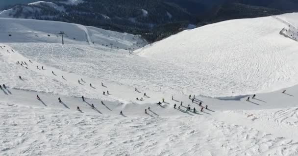 Ludzie ślizgają się po stoku na nartach i snowboardach. Stok narciarski - pionowy widok z góry — Wideo stockowe