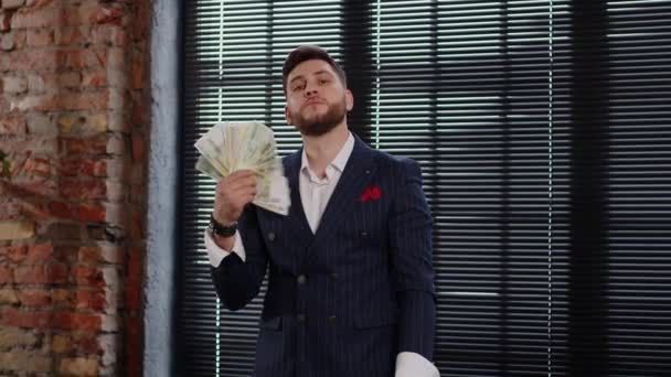 Красивый молодой бизнесмен держит вентилятор из бумажных денег и радуется успеху — стоковое видео