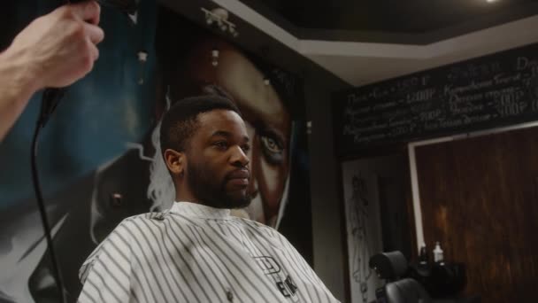 Der Friseur passt das Peignoir des Afroamerikaners an. Toleranz — Stockvideo