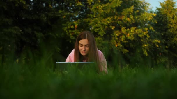 Gyönyörű fiatal lány diák dolgozik egy laptop egy parkban, közel az egyetemhez — Stock videók