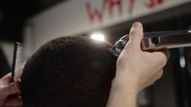 Makas, Afrikalı bir Amerikalının kıvırcık saçlarını kesiyor.