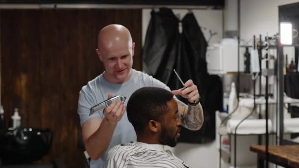 Estilista de pelo blanco haciendo peinado a guapo joven afroamericano hombre — Vídeo de stock