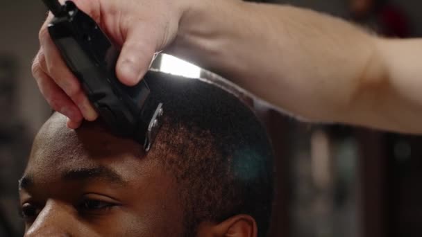Vit kille klipper sig till en ung glad afrikansk amerikan i en vacker frisersalong. — Stockvideo