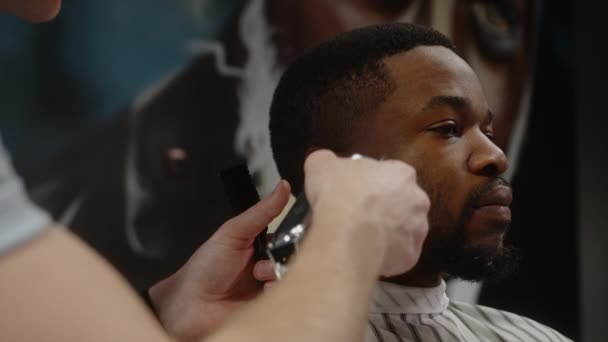Tipul alb face o tunsoare pentru un tânăr afro-american bucuros într-o frizerie frumoasă — Videoclip de stoc