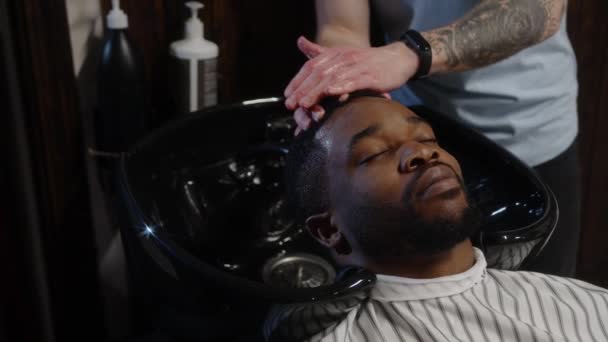 Barberは彼の髪を洗い、美容師のクライアントにマッサージを与えます-閉じる — ストック動画