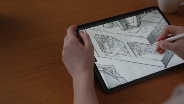 Una talentuosa concept artist ragazza disegna su un tablet con display digitale un progetto di un futuro casual gioco 3D, seduta a un tavolo a casa in salotto — Video Stock