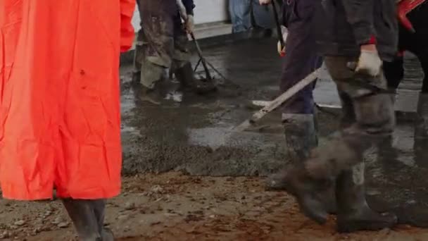 Arbetstagare häller och jämnar ett betonggolv i en industribyggnad — Stockvideo