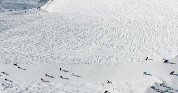 Ludzie ślizgają się po stoku na nartach i snowboardach. Stok narciarski - pionowy widok z góry — Wideo stockowe