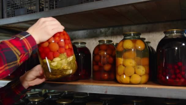Las manos masculinas ponen frutas y verduras enlatadas en un estante en un sótano o refugio antibombas. Existencias de alimentos en caso de guerra — Vídeos de Stock