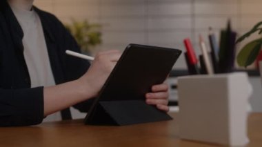 Tabletteki kalemle çalışan bir kız elinin yakın çekimi. Dijital sanatçı bir çizim çizer