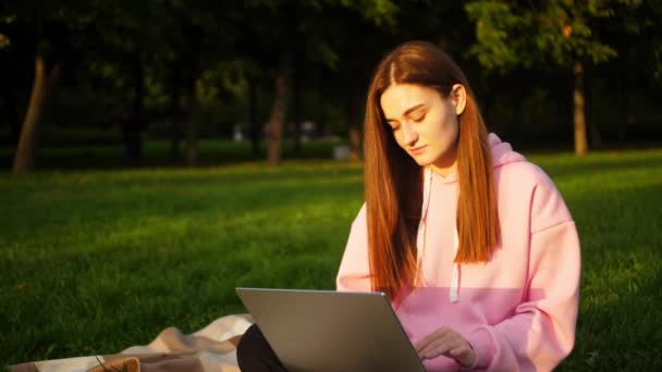 Piękna młoda dziewczyna student pracuje na laptopie w parku w pobliżu uniwersytetu — Wideo stockowe