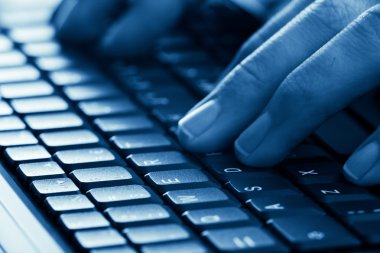 Eller dizüstü bilgisayarda yazıyor.