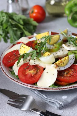 Domatesli sağlıklı salata, mozarella, zeytin, roka ve hafif arkaplanlı yumurta. Dikey