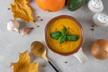Açık gri arka planda bir kasede kremalı balkabağı ve kabaklı çorba. Yukarıdan görüntüle