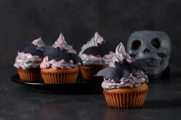 Cupcakes met kleurrijke crème versierd met vleermuizen voor Halloween feest op donkere achtergrond — Stockfoto