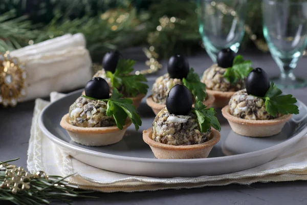 Gustare de vacanță în tarte cu ciuperci, ouă și măsline negre pe un fundal gri Fotografie de stoc