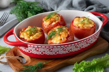 Açık gri arka planda tavuk ve peynirli fırında domates.