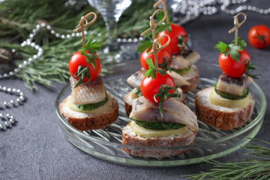 Çavdar ekmeğinde tuzlanmış ringa, salatalık, haşlanmış patates ve vişneli domates ve koyu gri arka planda..