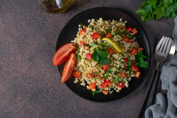 茶色の背景にブルグルとパセリと伝統的な東洋のサラダTabouleh トップビュー — ストック写真