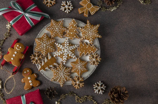Cookie-uri în formă de brad de Crăciun, om turtă dulce și fulgi de zăpadă pe fundal maro. Felicitări festive de Crăciun. Privire de sus. Copiați spațiul Fotografie de stoc