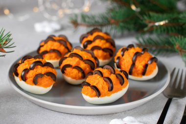 2022 yılı için morina ciğeri ve havuçla doldurulmuş yumurtadan yapılmış kaplan aperatifi gri arka planda.