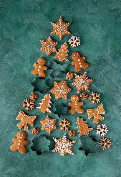 Christmas tree made of gingerbread cookies and molds for gingerbread on green background, Top view — Stock Photo, Image