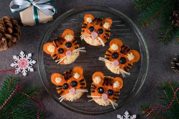 Тарталетки в виде забавных тигров на Новый 2022 год из колбасы, сыра, моркови и черных оливок на коричневом фоне — стоковое фото