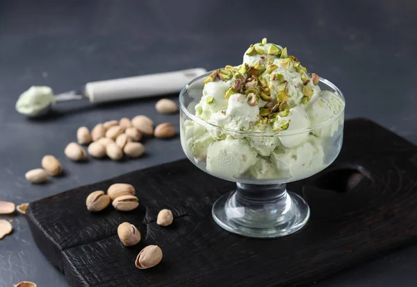 Lody pistacjowe z orzechami pistacjowymi szklaną misą lodową na ciemnym tle, w formacie poziomym — Zdjęcie stockowe