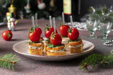 Kahverengi arka planda kızarmış tavuk, peynir ve kiraz domatesli kanepeler.