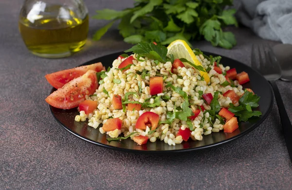 Kahverengi arka planda bulgur ve maydanozlu geleneksel doğu salatası Tabouleh, yakın plan.