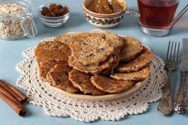 Los buñuelos de avena con pasas se espolvorean con jarabe dulce y se sirven para el desayuno con una taza de té y mermelada. — Foto de Stock