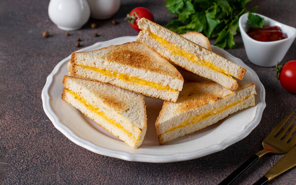 Sandwiches with egg and cheese fried in pan served with tomato sauce for breakfast on white plate