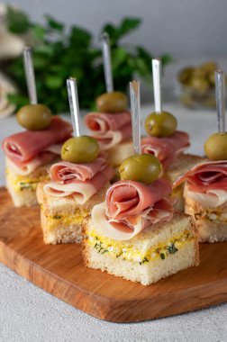 Jambonlu kanepe ve tahtada peynirli kızarmış beyaz ekmek üzerine zeytin.