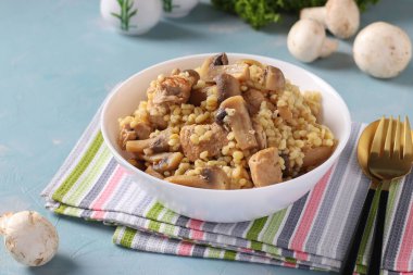 Bolgur ve şampiyonlarla dolu domuz eti beyaz bir kâsede servis edilir, ev yapımı, doyurucu bir yemektir.