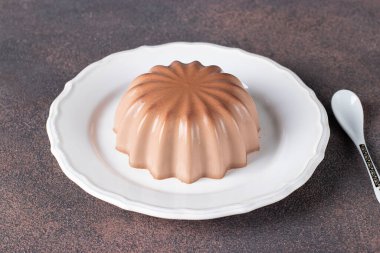 Kahverengi arka planda beyaz tabakta çikolatalı pelte