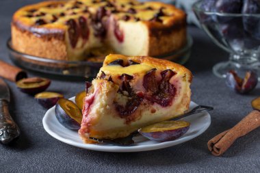 Erikli ve tarçınlı ev yapımı kaymak turtası, yemeye hazır, gri arka planda kesilmiş bir tabakla.