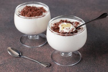 Ev yapımı krema veya sütlü pinepple, kahverengi arka planda iki fincanda çikolata parçacıkları serpiştirilmiş, tatlı pelte