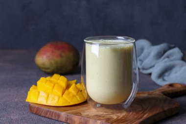 Lassi Mango, tahta tahtada camda, siyah arka planda. Hint sağIıklı mangolu soğuk içecek.