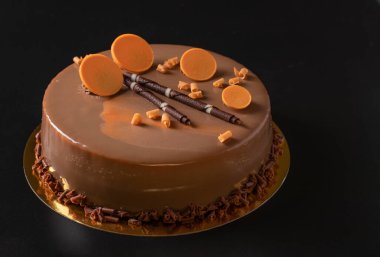 Siyah arka planda çikolatalı ve dekorlu kremalı pasta.