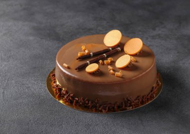 Koyu gri arka planda çikolata ve dekor olan kremalı pasta.
