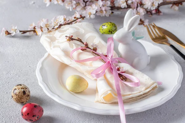 Mesa de Pascua con huevos de codorniz, servilleta y conejo en un plato blanco sobre una mesa gris claro. Una cena elegante. Primer plano — Foto de Stock