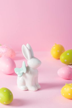 Paskalya tavşanı ve pembe arka planda renkli yumurtalar. Paskalya dikey tebrik kartı