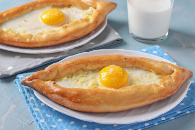 Adjarian 'da Khachapuri, açık turtalar sülüguni peyniri ve yumurta sarısı açık mavi arka planda tabak şeklinde bir tekne, geleneksel Gürcü mutfağı.