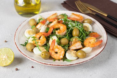 Karidesli salata, bıldırcın yumurtası, zeytin ve roka, zeytin yağı ve limon suyu ile kaplanmış gri arka plan.