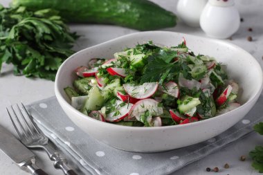 Salata salatalıkları, turplar ve zeytin yağıyla kaplanmış taze otlar gri arka planda salata kasesinde