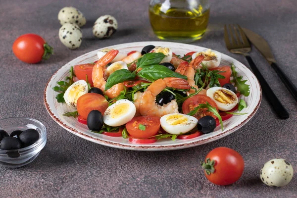 Salad with shrimps, quail eggs, arugula, cherry tomatoes and black olives on plate on brown background —  Fotos de Stock