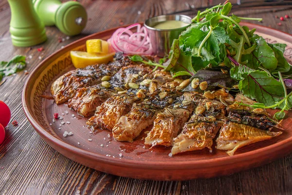 Ahşap masada soslu, soğanlı, limonlu ve yeşil salatalı ızgara uskumru.