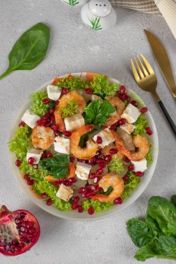 Karidesli salata, ananas, feta ve nar tohumları tabakta yeşil marul yaprakları, açık gri arka plan, Üst Manzara