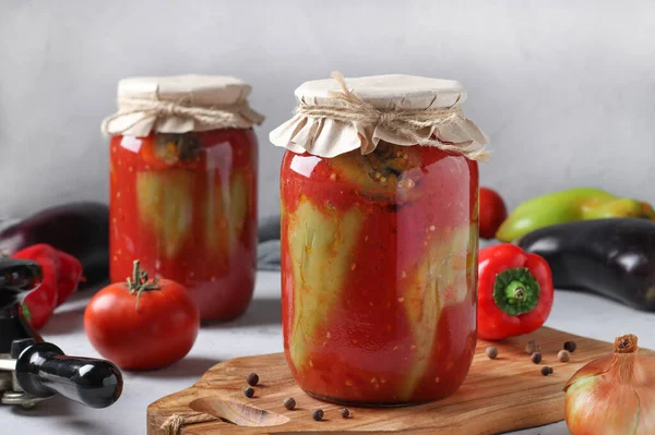 Pimientos rellenos de berenjena y cebolla, en salsa de tomate, en dos frascos de vidrio sobre fondo gris claro —  Fotos de Stock