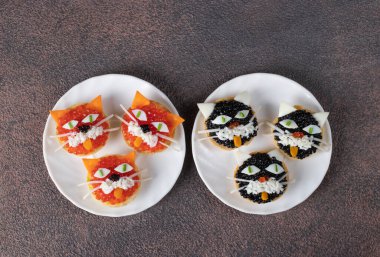 Kahverengi arka planda iki yuvarlak tabakta peynirli, yumurtalı ve havyarlı turta yavruları.